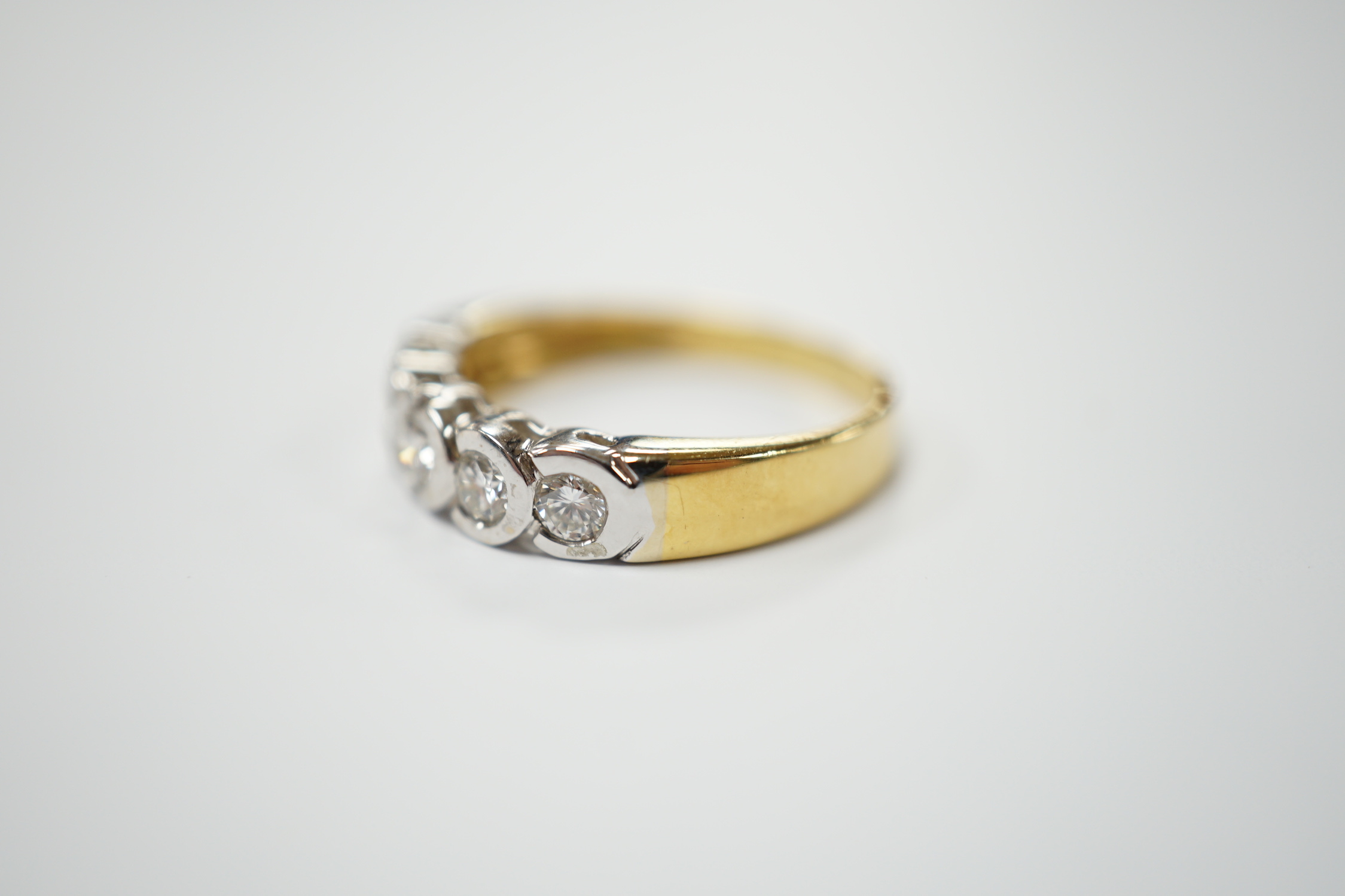 A modern 18ct gold and collet set five stone diamond half hoop ring, size O, gross weight 3.5 grams.